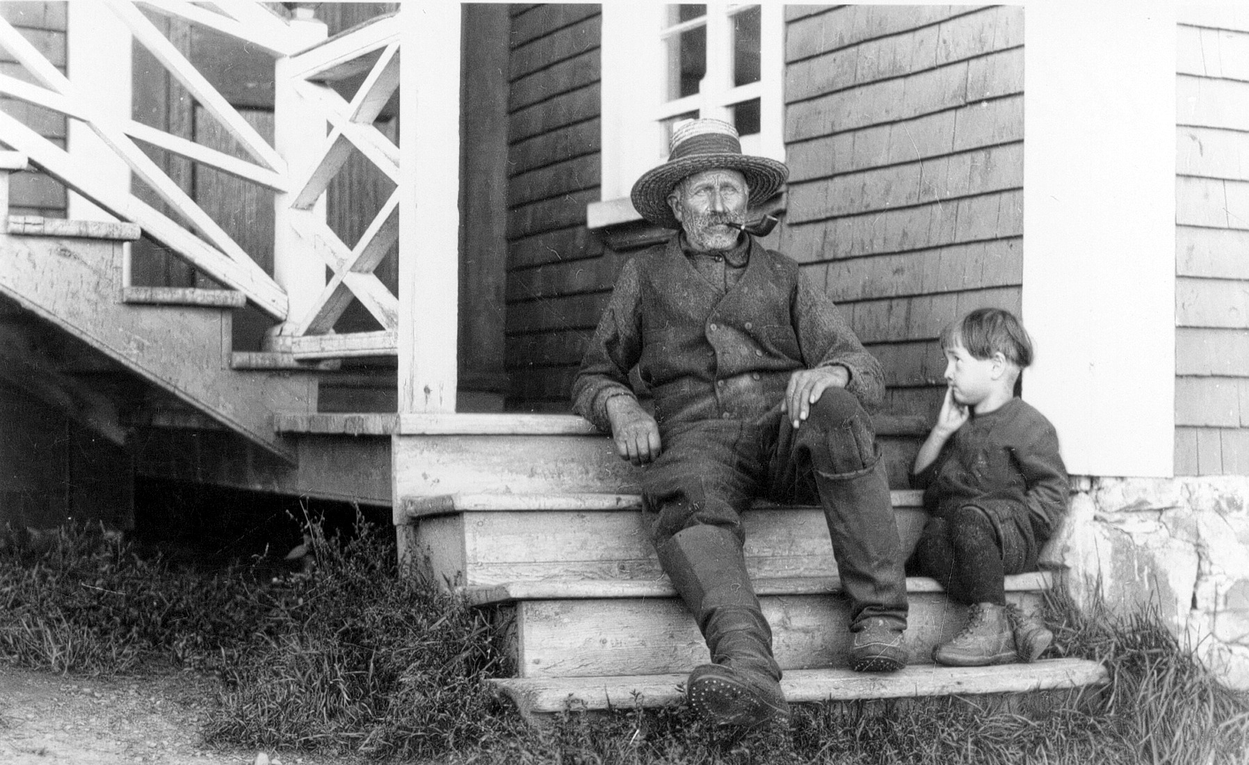 Un vieil homme et un garçon d'environ trois ans assis dans l'escalier du perron de la maison des Dumont.