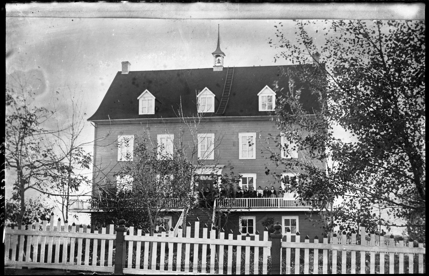 Couvent de Saint-Alexandre-de-Kamouraska vu de face avec les élèves debout sur la galerie.