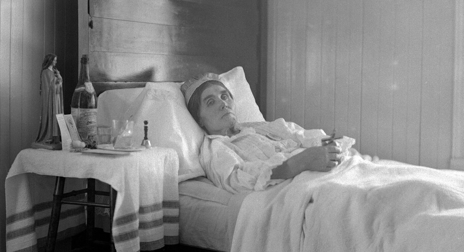 Marie Pelletier très malade, le visage émacié, alitée et tenant un crucifix.