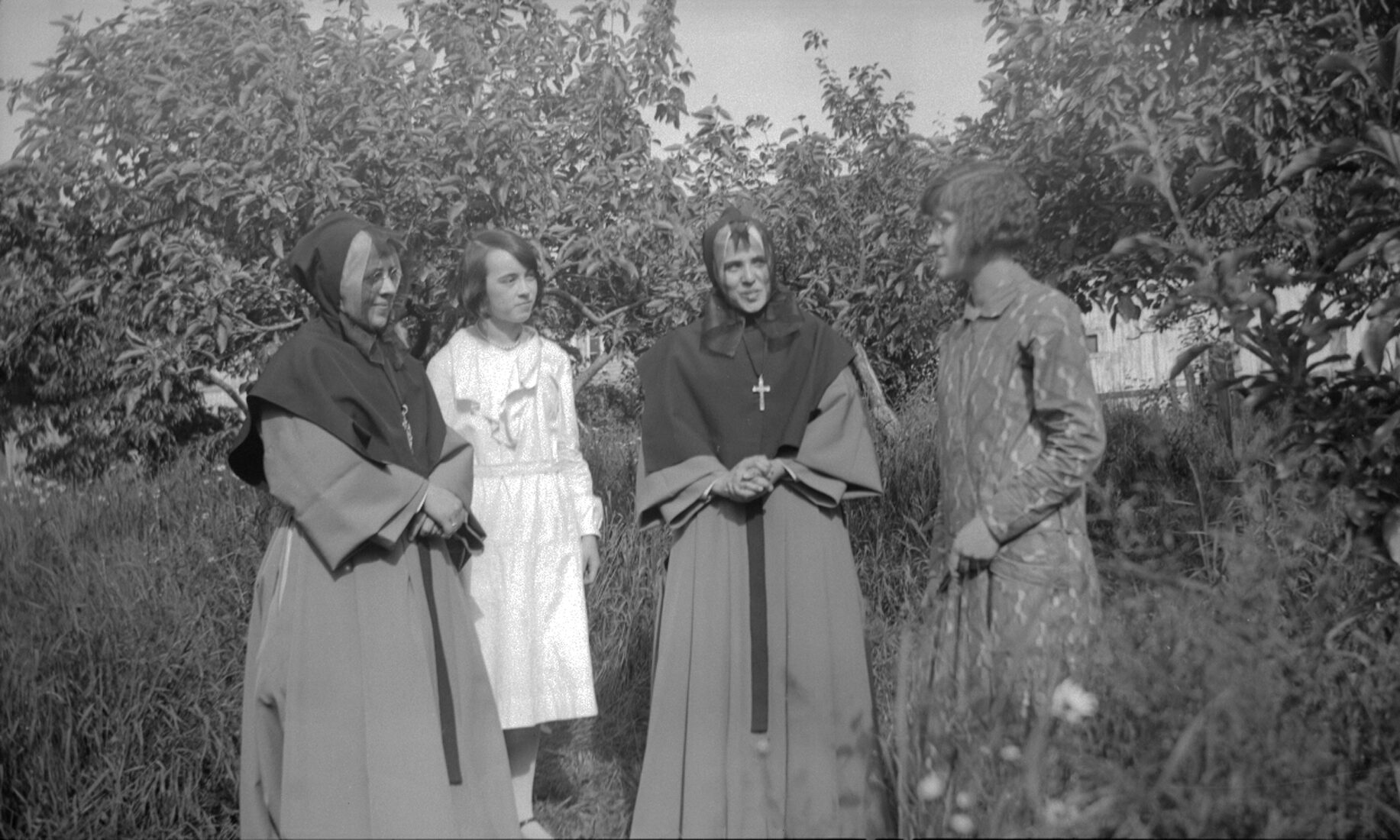 Deux religieuses et deux jeunes femmes au milieu du verger des Dumont.