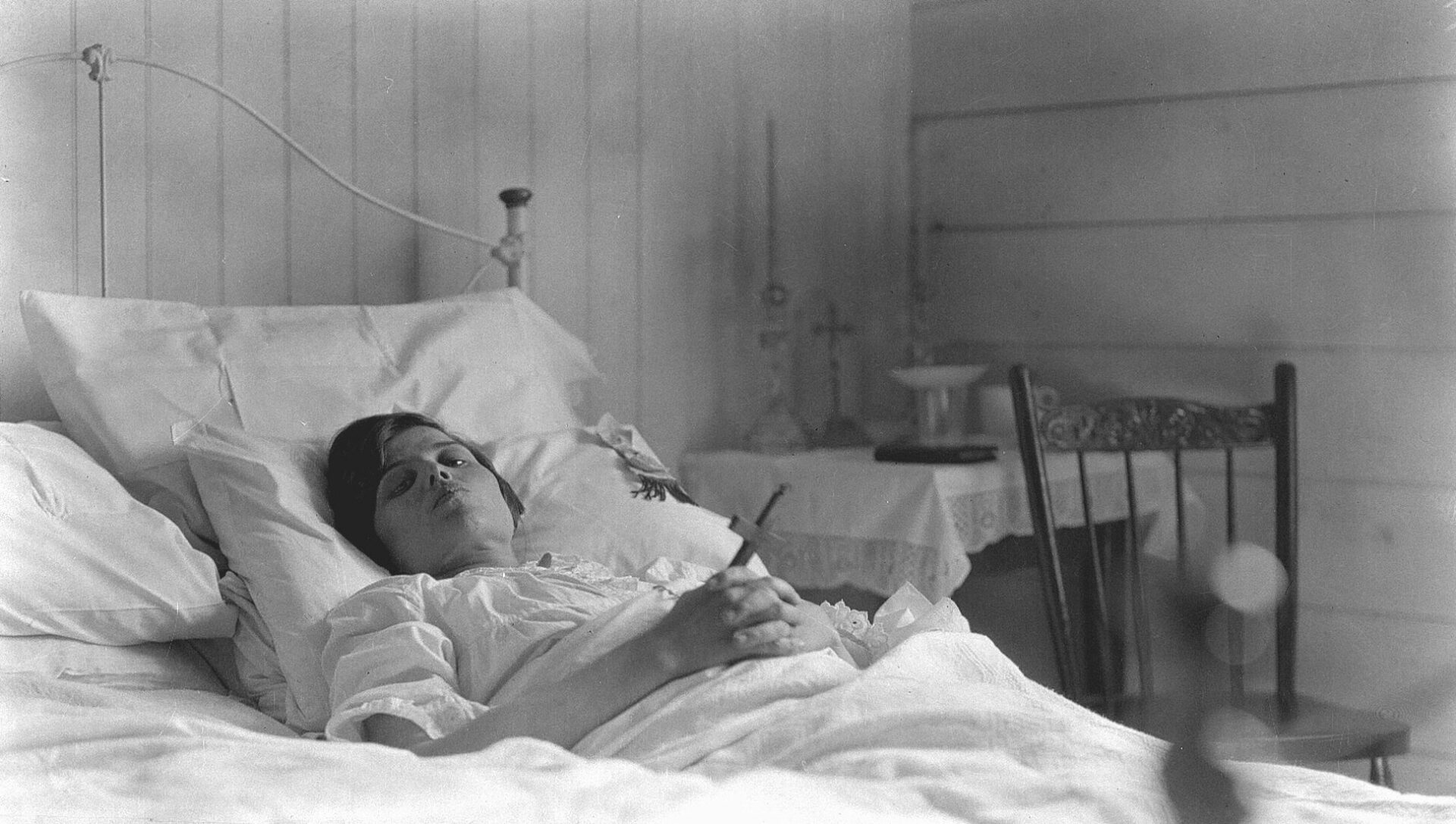 Marie-Louise Dumont très malade, le visage émacié, alitée et tenant un crucifix.
