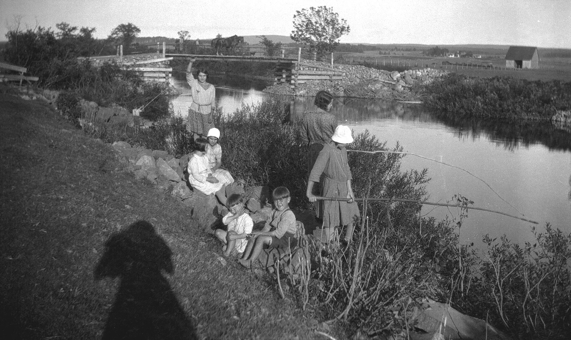 Groupe de jeunes gens dans un environnement champêtre et pêchant sur le bord d'une rivière.