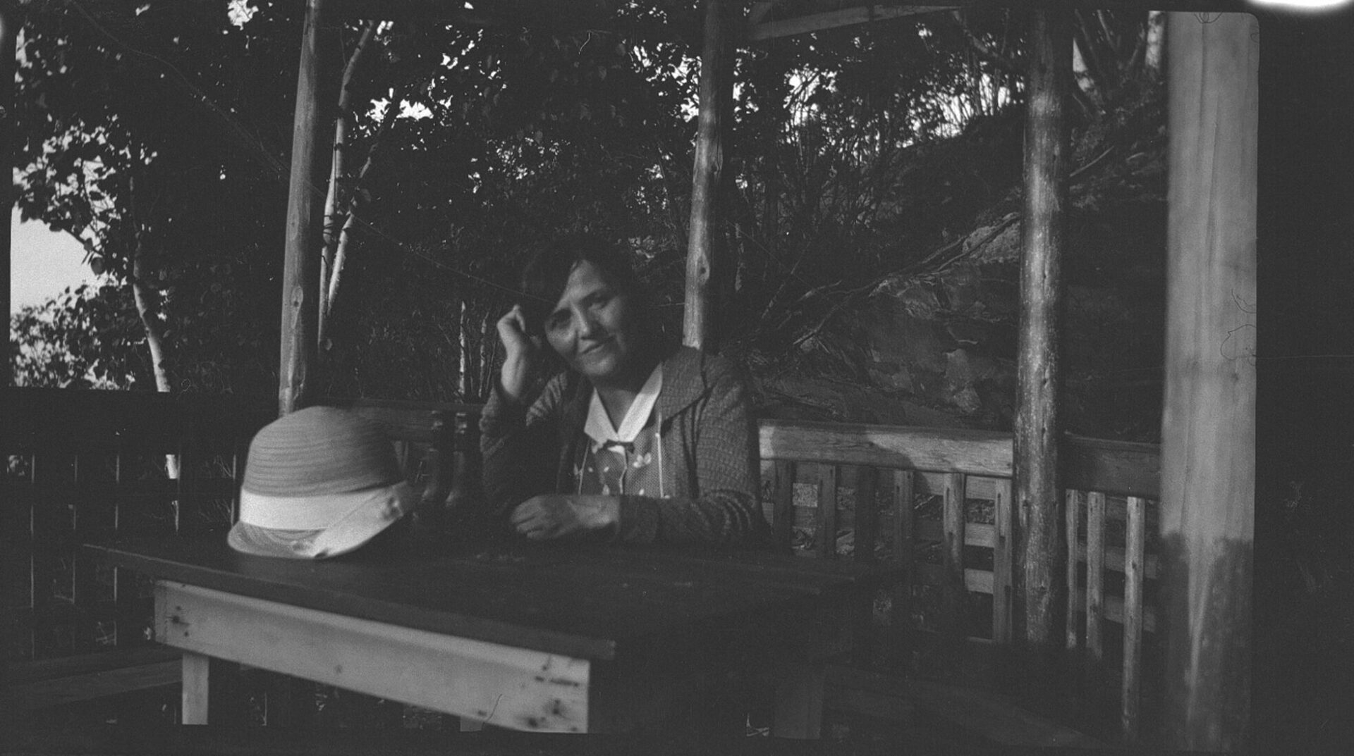 Marie-Alice Dumont attablée dans une gloriette installée dans un environnement naturel.