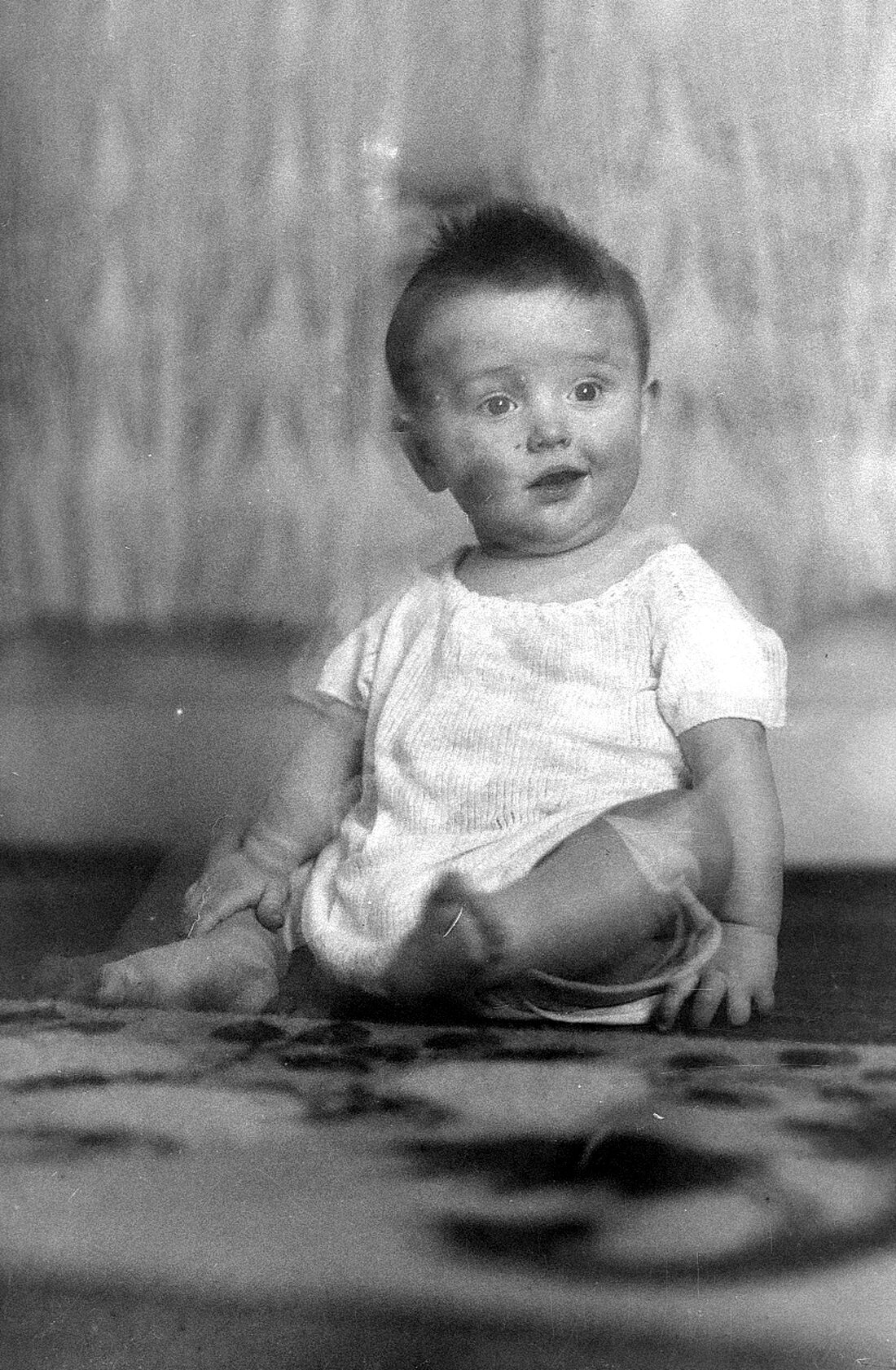 Portrait au ras du sol d'Origène Dumont âgé d'un an dans un cliché rendu flou par le mouvement du bébé.