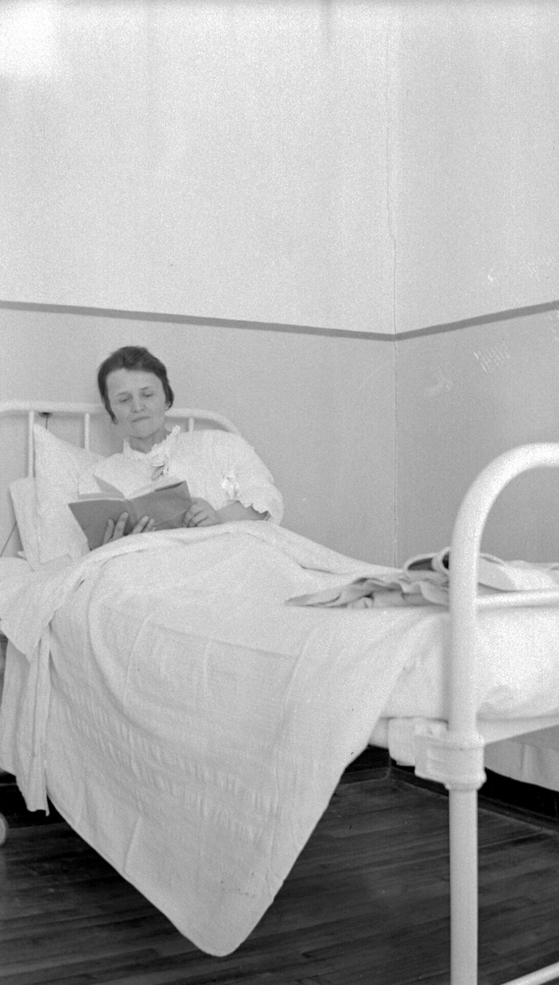 Marie-Alice Dumont âgée d'environ 40 ans lisant un livre alitée dans un lit d'hôpital.