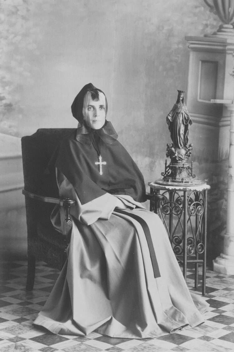 Portrait en studio d'une religieuse assise dans un fauteuil.