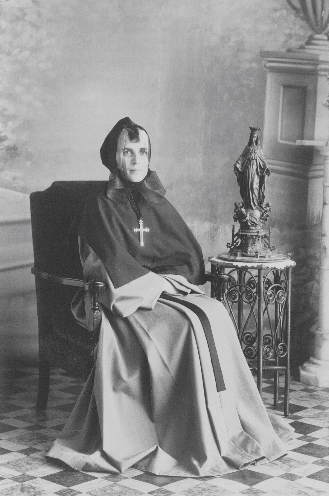 Portrait en studio d'une religieuse assise dans un fauteuil.