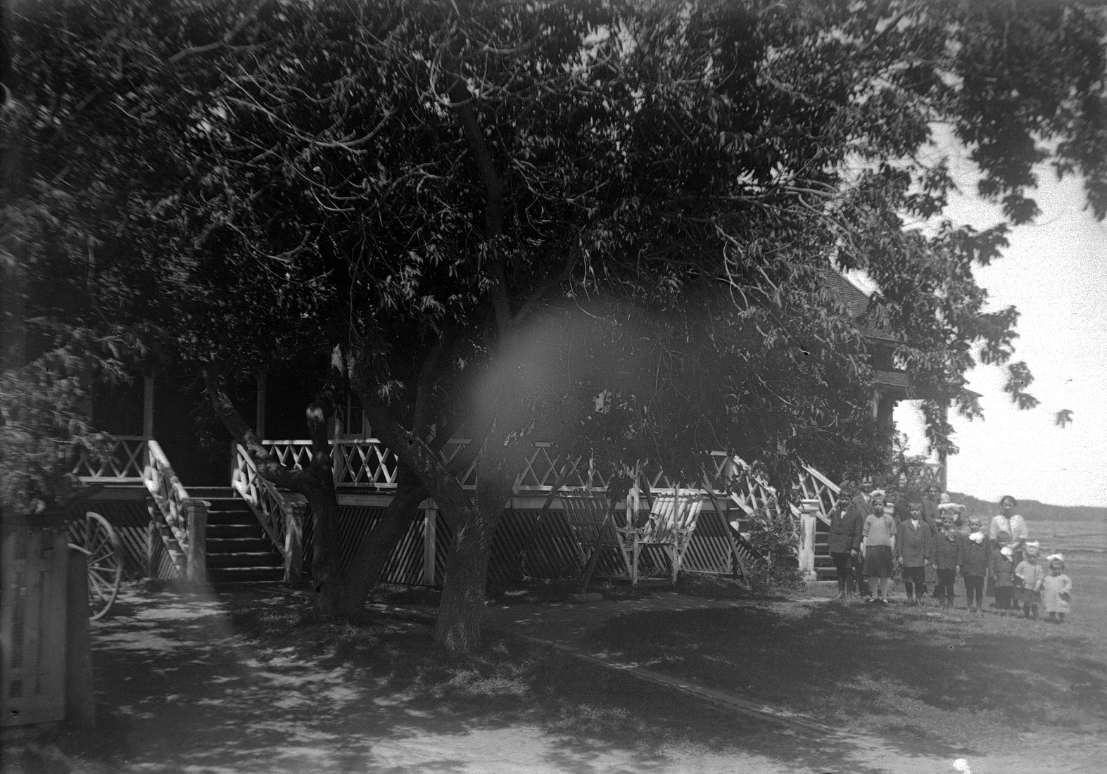 Une famille comprenant les deux parents et 10 enfants posant près de leur maison et d'un très grand arbre.