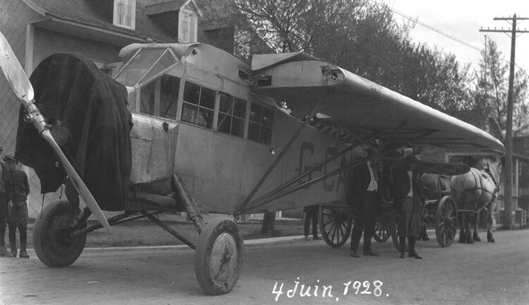 Un avion tiré par des chevaux transporté dans la rue d'un village.