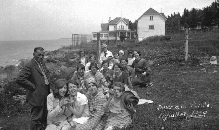 Un groupe d'une quinzaine de jeunes femmes enjouées accompagnées d'un homme près du fleuve Saint-Laurent.