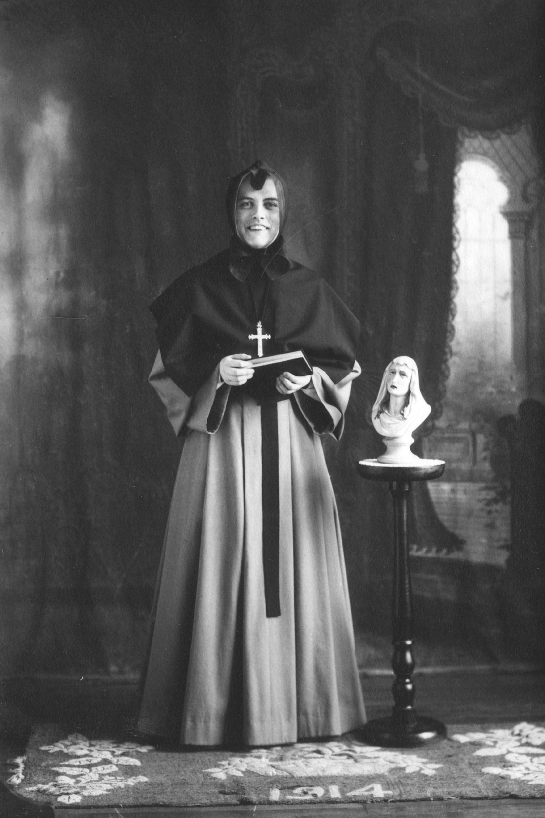 Portrait de studio d'une religieuse tenant un livre dans ses mains et souriant à la caméra.