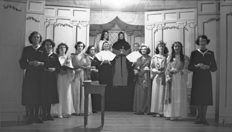 Portrait d'une troupe de théâtre posant sur la scène et composée de couventines.