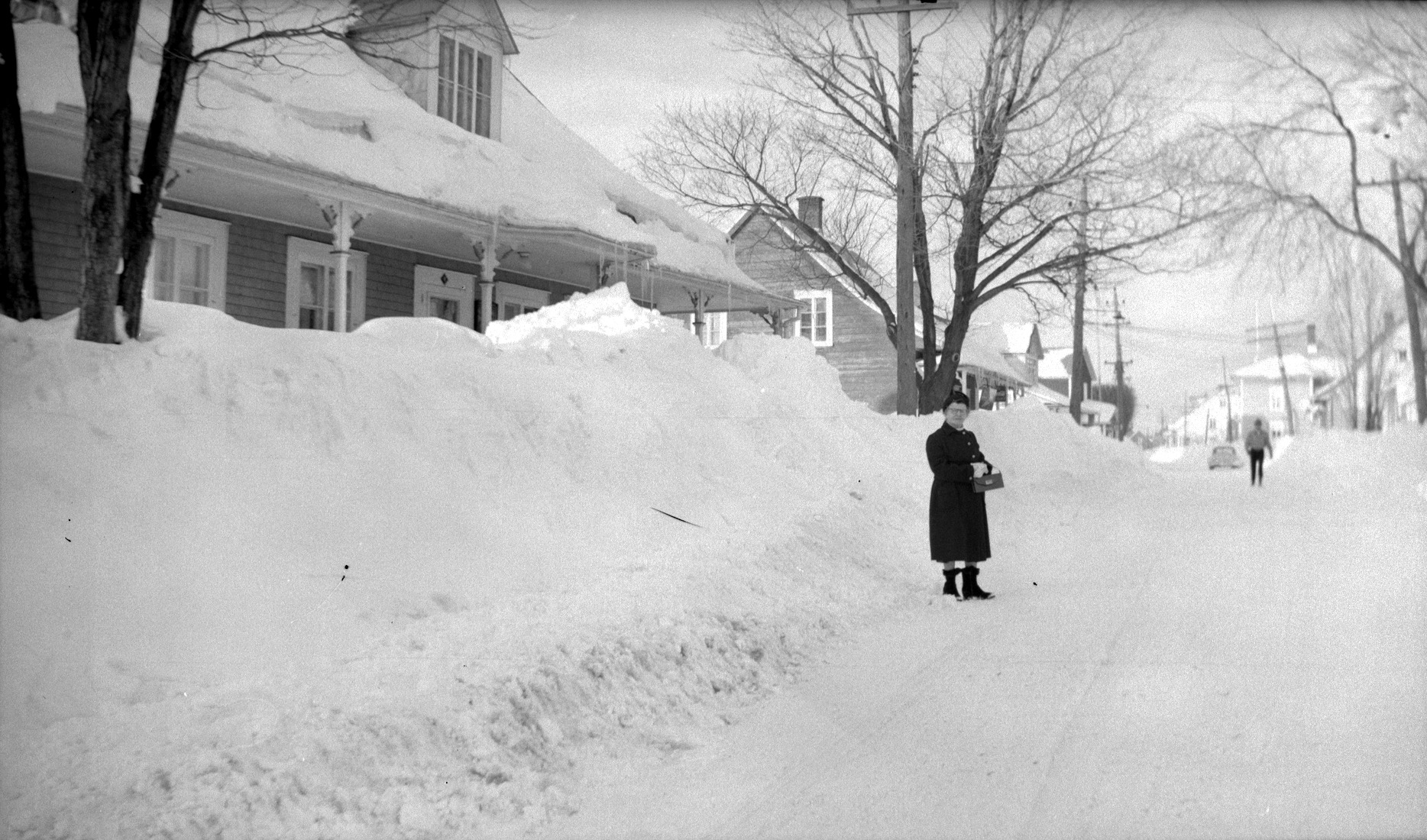 Marie-Alice Dumont élégamment vêtue posant à l'extérieur devant un grand banc de neige cachant une partie de sa maison.