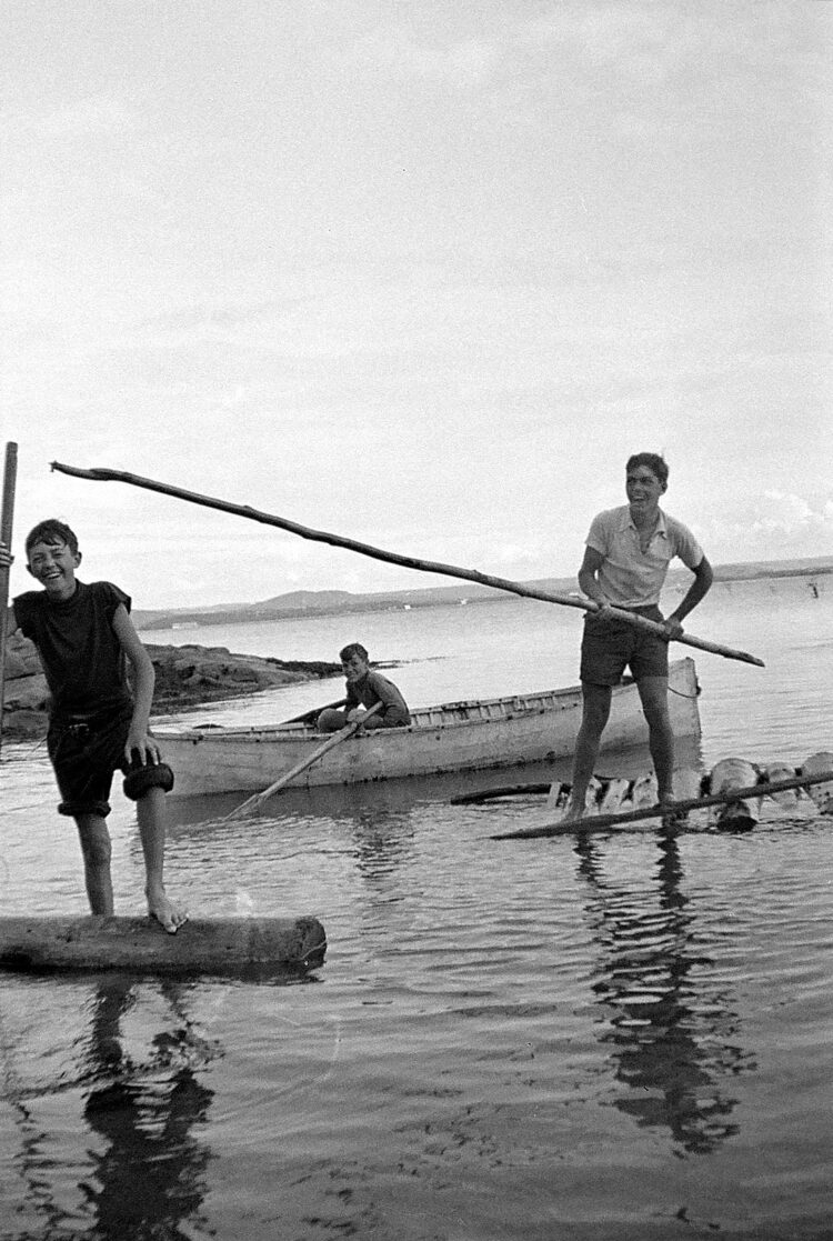 Trois jeunes garçons en baignade dans le fleuve Saint-Laurent et se taquinant.