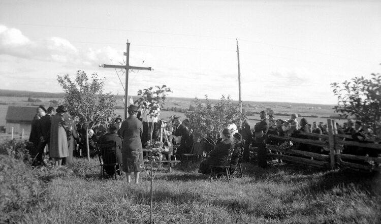 Cérémonie en plein air d'inauguration d'une croix de chemin rassemblant des dizaines de personnes.