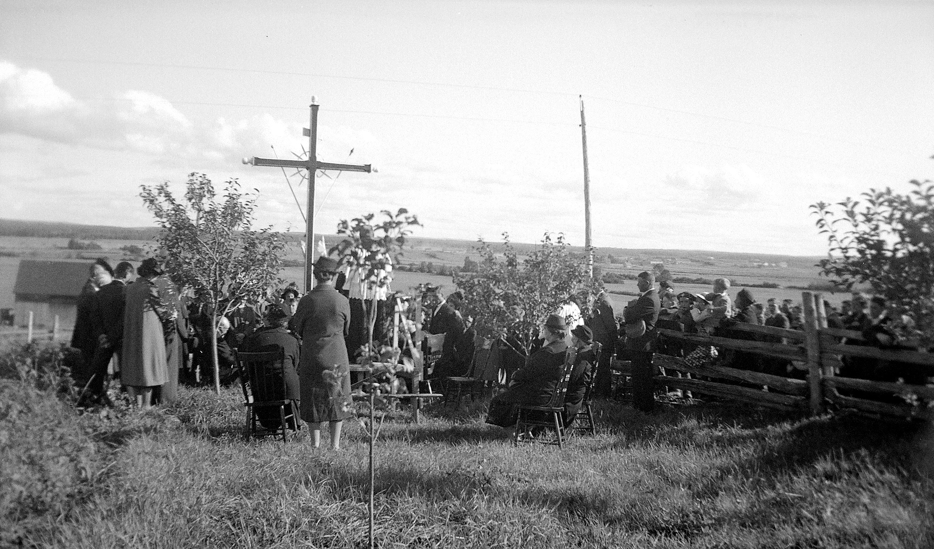 Cérémonie en plein air d'inauguration d'une croix de chemin rassemblant des dizaines de personnes.
