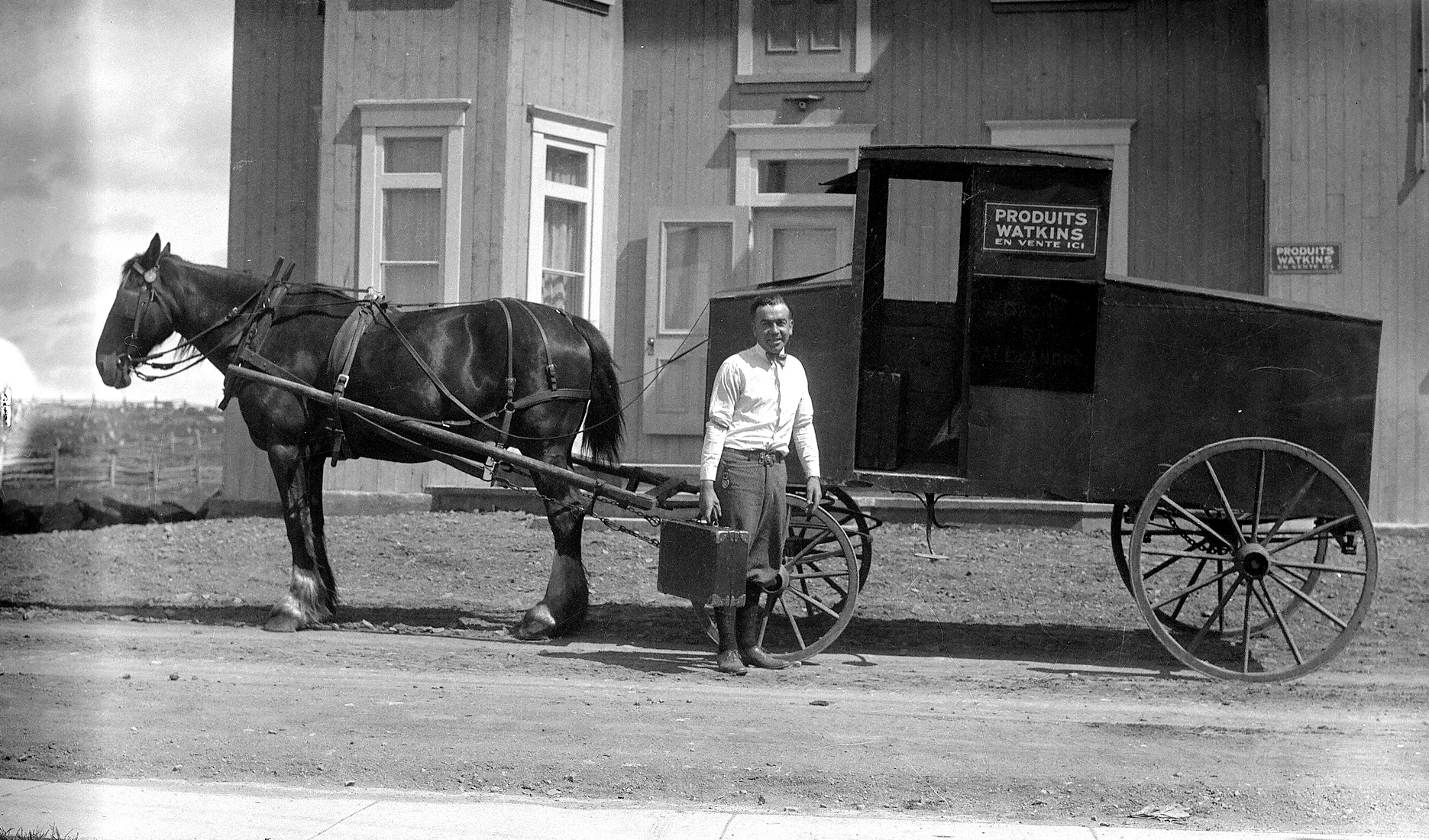 Un marchand itinérant de "Produits Watkins" devant son commerce sur roues tiré par un cheval.