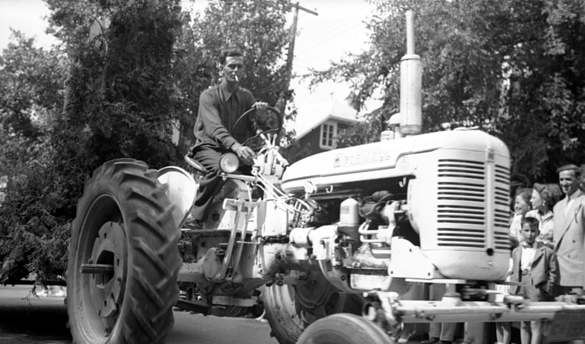Un homme au volant d'un tracteur tirant un char allégorique sous le regard d'une foule.