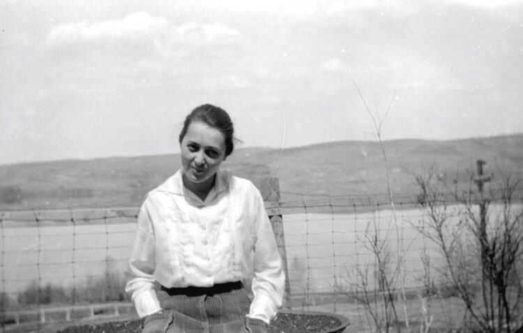 Portrait d'Aline Cloutier âgée d'environ 15 ans avec en arrière-plan un lac et des collines.