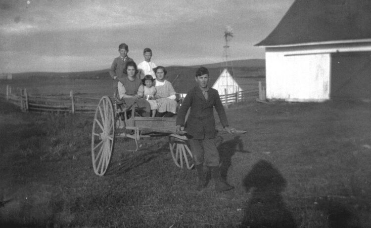 Cinq jeunes neveux et nièces de Marie-Alice Dumont assis dans une charrette tiré par un autre neveu de la photographe.
