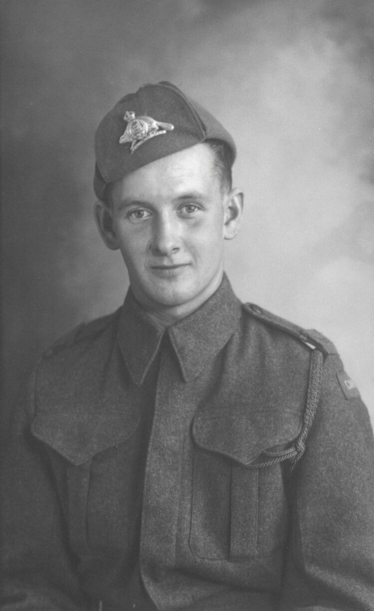 Portrait studio en buste d'un jeune en habits de militaire dans un décor dépouillé.