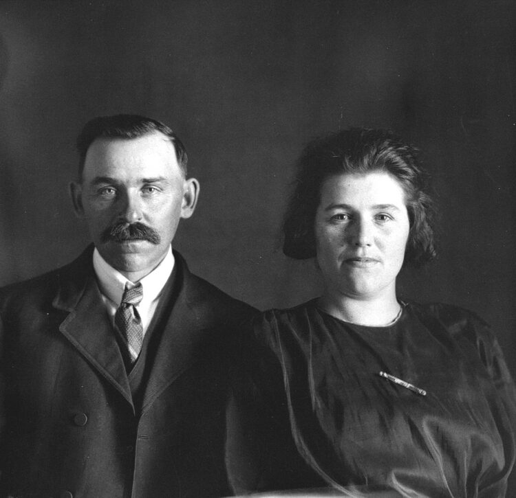 Portrait de studio en buste d'Émilia Dumont et de Flavius Ouellet âgés d'environ 35 et 40 ans dans un décor dépouillé.