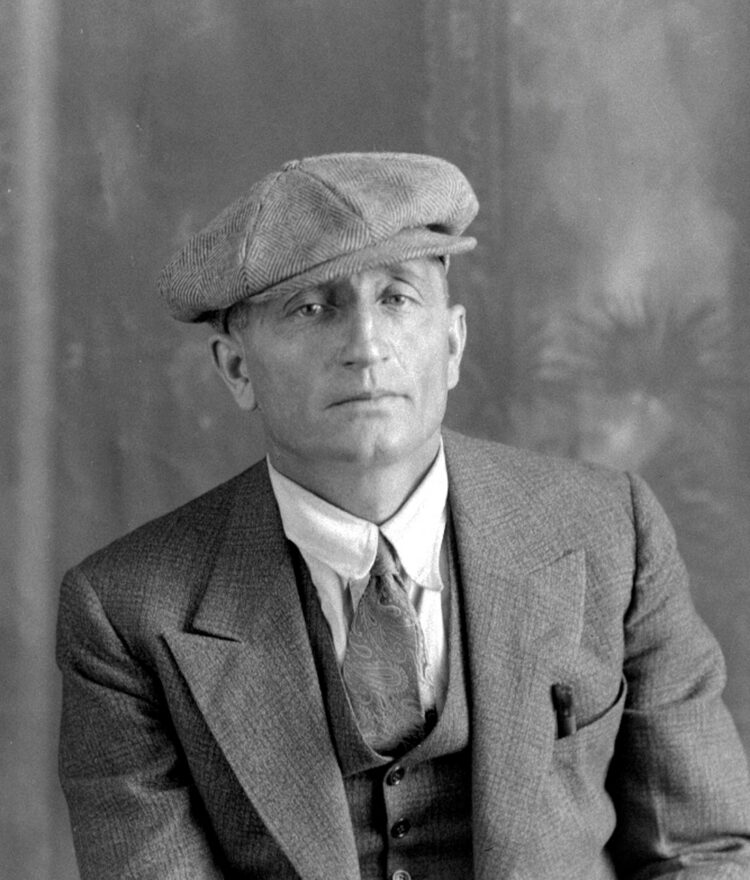 Portrait studio en buste d'un homme d'âge mûr vêtu élégamment et portant la casquette.