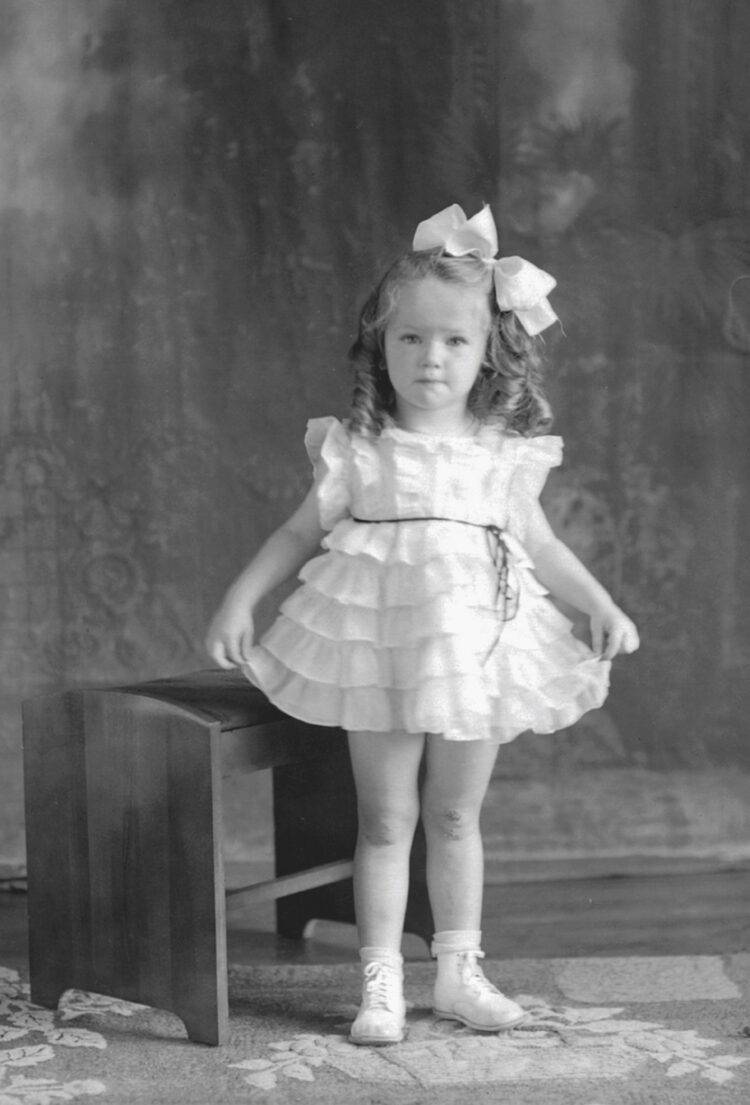 Portrait studio d'une fillette portant une robe courte et blanche.