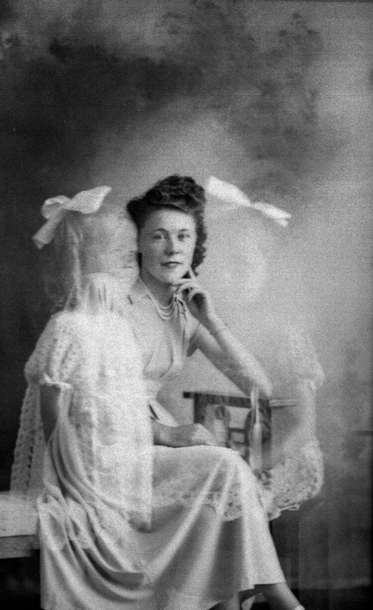 Portrait studio d'une femme assise sur un banc et à ses côtés, par effet de superposition due à une double exposition du négatif, deux fillettes.