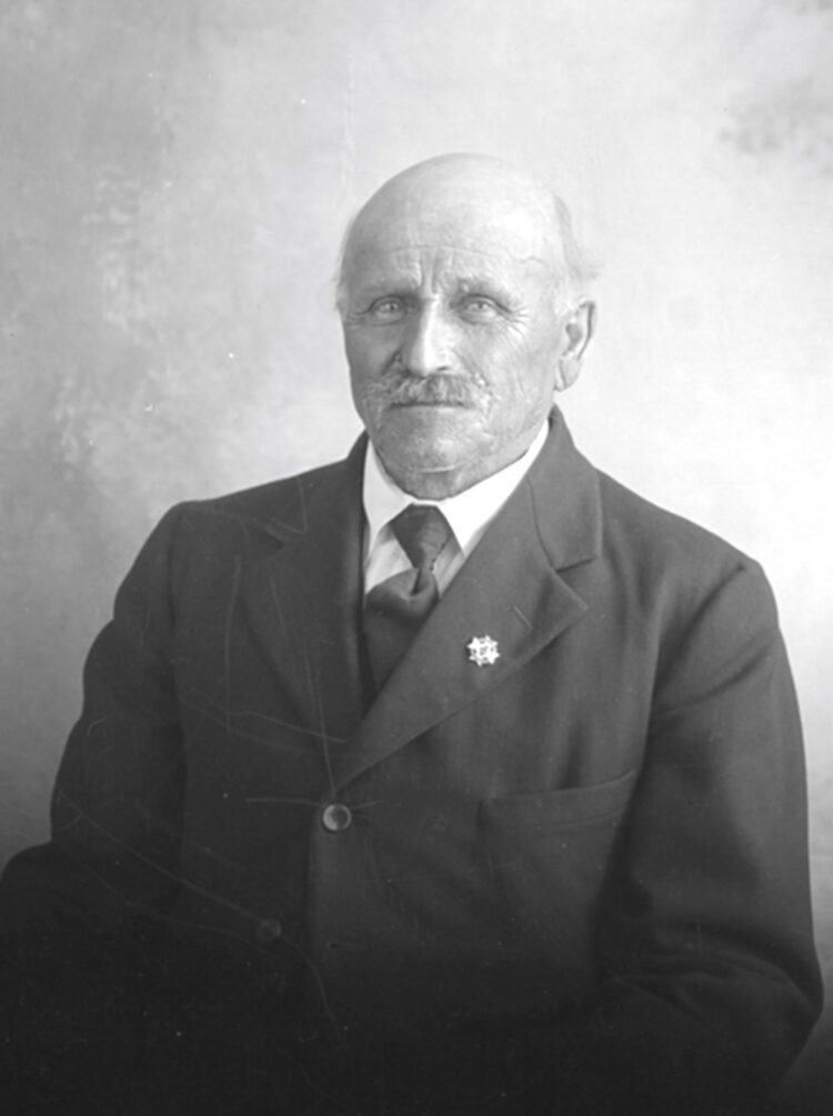 Portrait de studio en buste d'Uldéric Dumont âgée d'environ 75 ans dans un décor dépouillé.