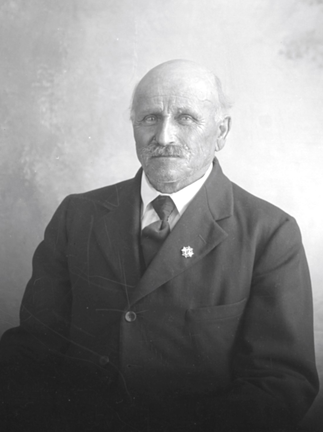 Portrait de studio en buste d'Uldéric Dumont âgée d'environ 75 ans dans un décor dépouillé.