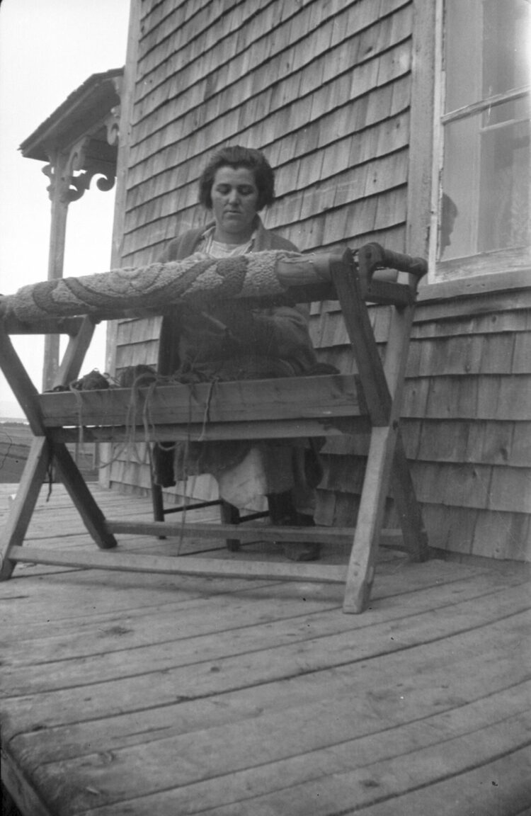 Émilia Dumont à la fabrication d'un tapis, installée sur la galerie d'une maison.