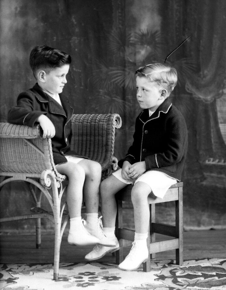 Portrait studio de deux jeunes garçons assis l'un en face de l'autre et se regardant dans les yeux.