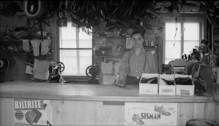 Un homme se tenant debout derrière le comptoir d'une cordonnerie.