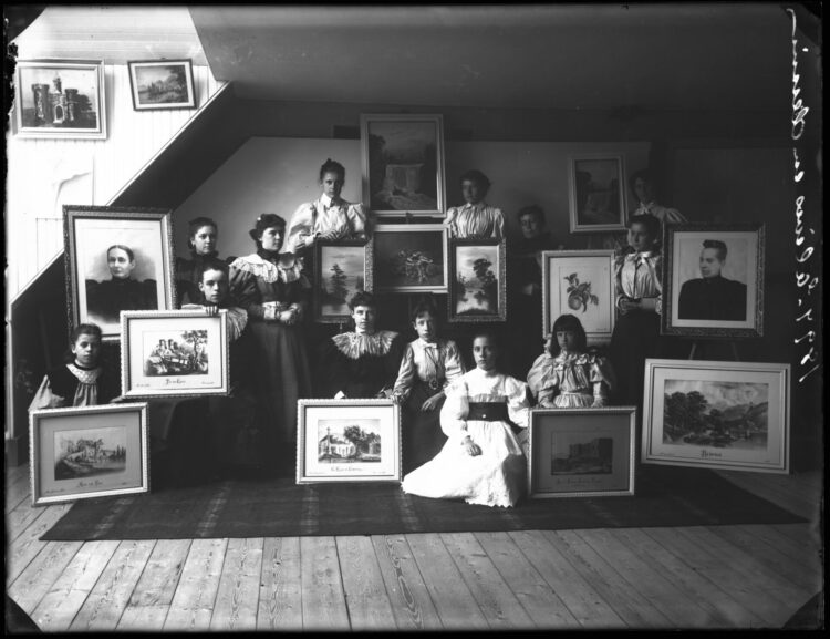 Un groupe de treize élèves montrant chacune un tableau réalisé en classe de peinture.