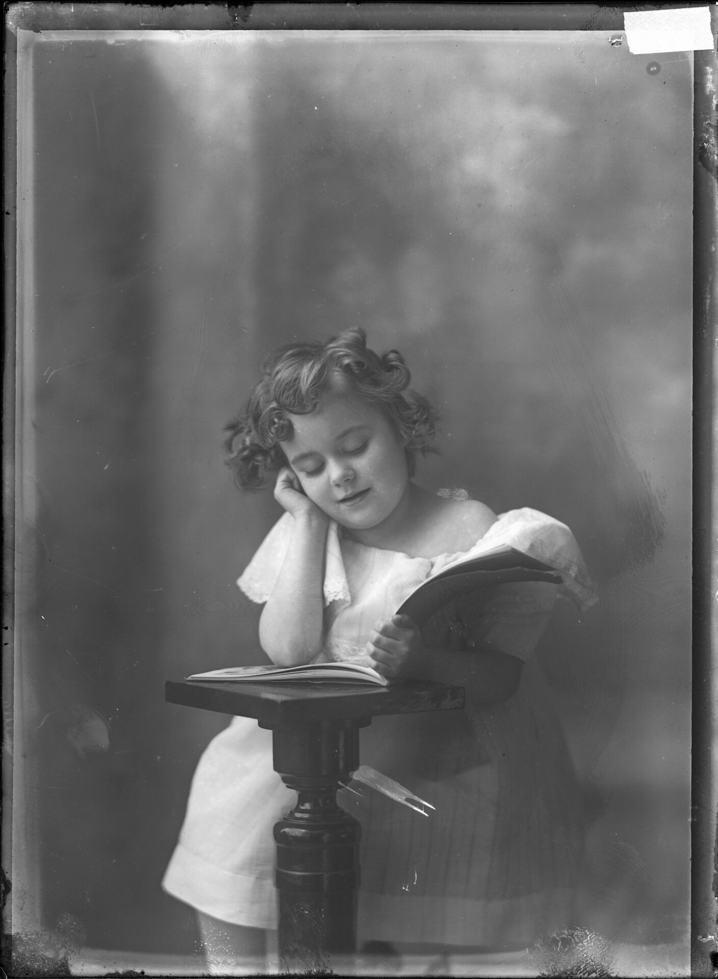 Une jeune orpheline posée en studio lisant un livre.