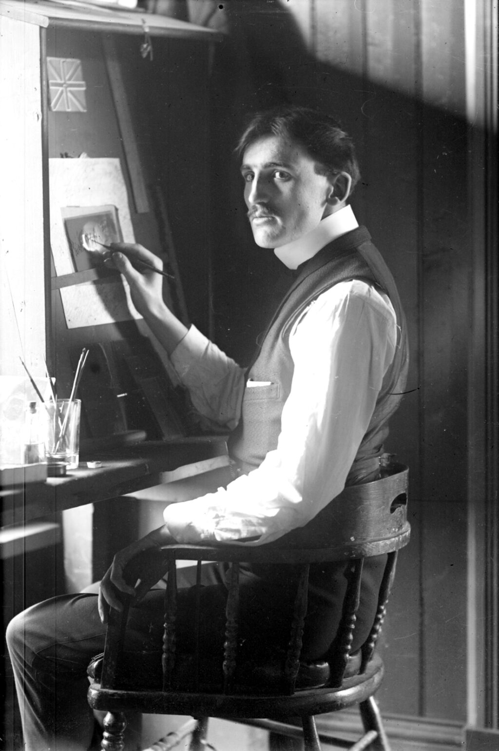 Portrait d'Ulric Lavoie âgé d'environ 30 ans en train d'effectuer la retouche d'une photo pinceau à la main.