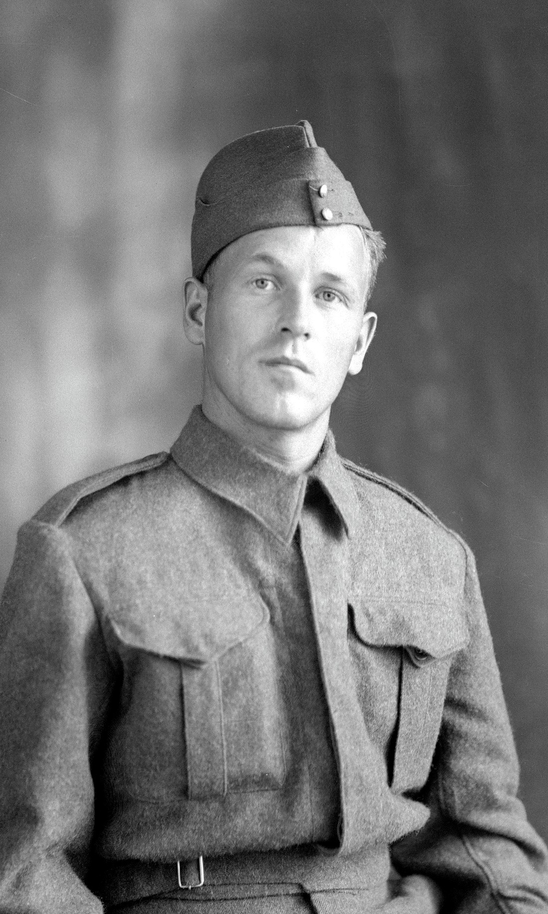 Portrait en buste d'un jeune homme en habits de militaire dans un décor dépouillé.