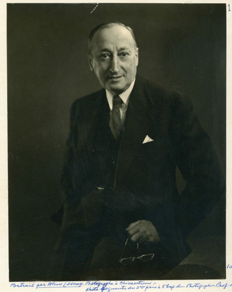 Portrait studio d'un homme élégamment vêtu dans un décor complètement dépouillé.