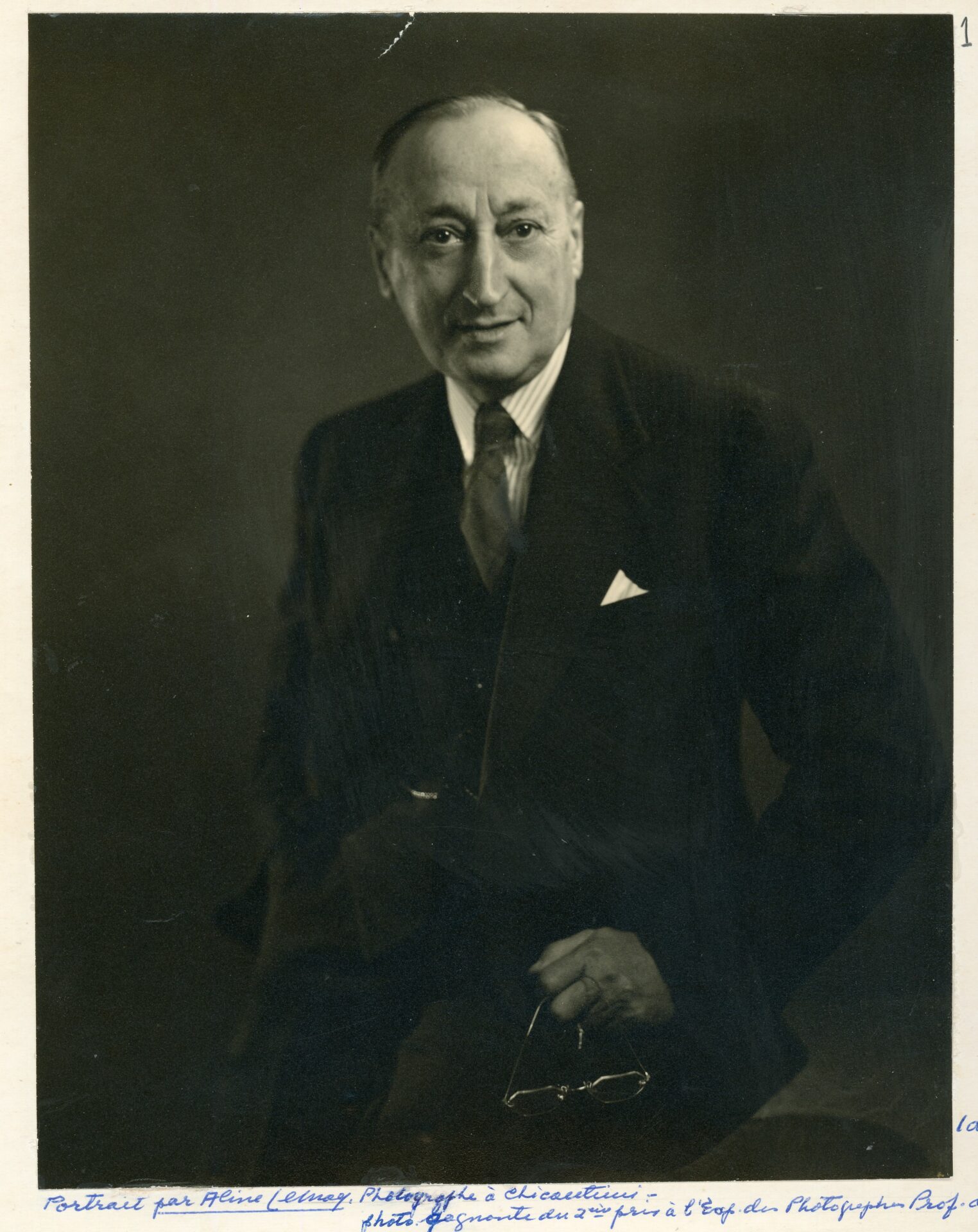 Portrait studio d'un homme élégamment vêtu dans un décor complètement dépouillé.