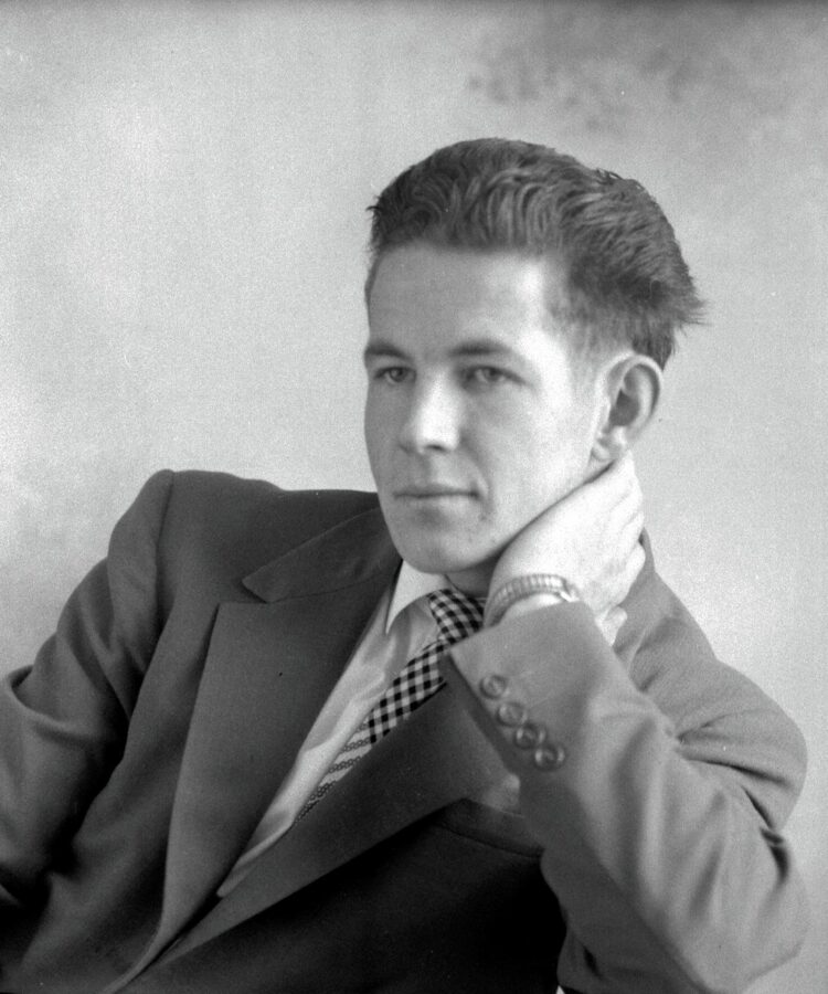 Portrait studio en buste d'un jeune homme assis et dont la nuque est appuyée dans l'une de ses mains