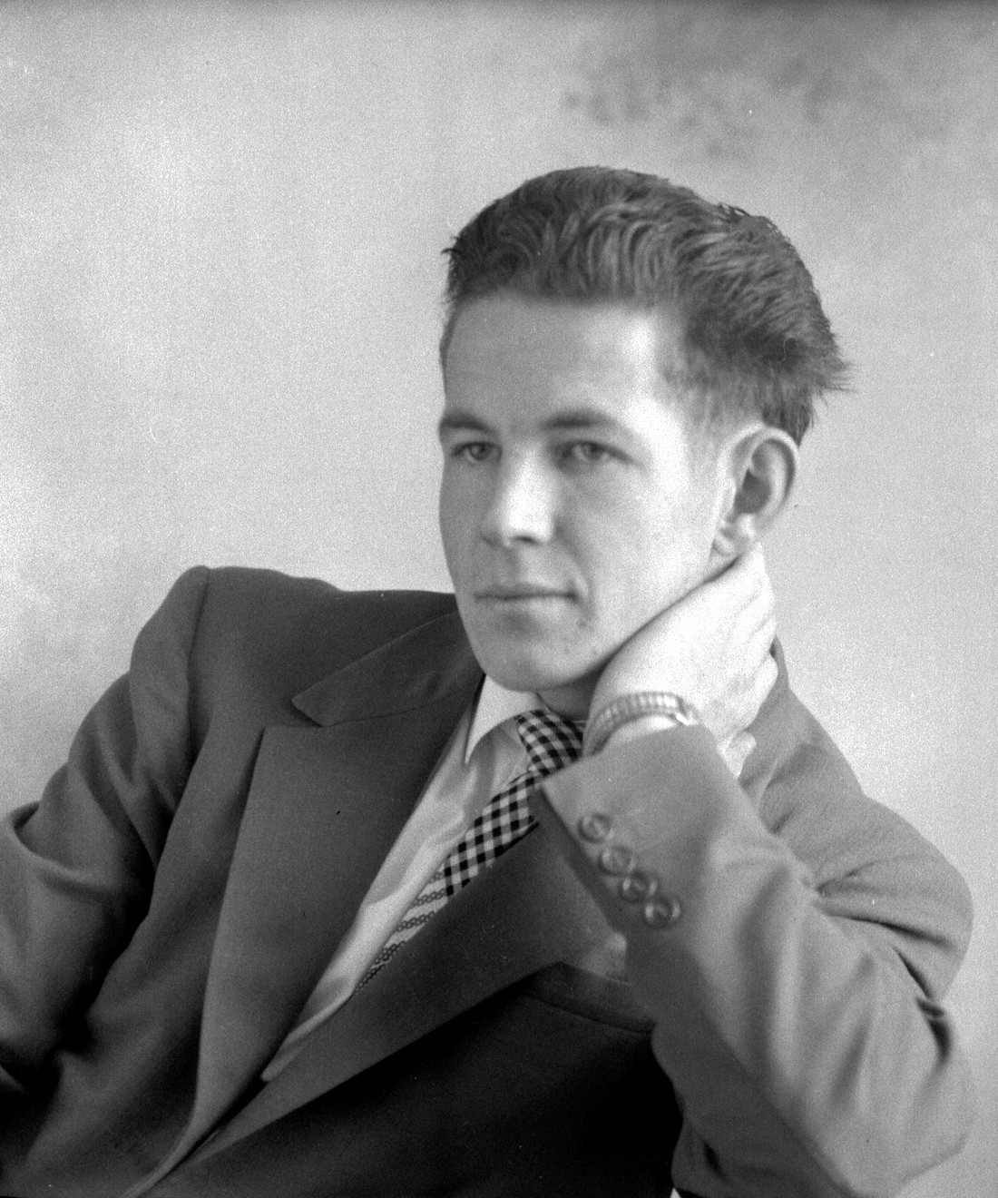 Portrait studio en buste d'un jeune homme assis et dont la nuque est appuyée dans l'une de ses mains