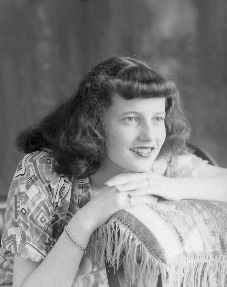 Une jeune femme posant en studio le menton appuyé sur les mains reposant sur un coussin