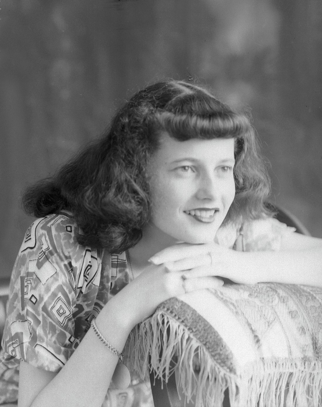 Une jeune femme posant en studio le menton appuyé sur les mains reposant sur un coussin