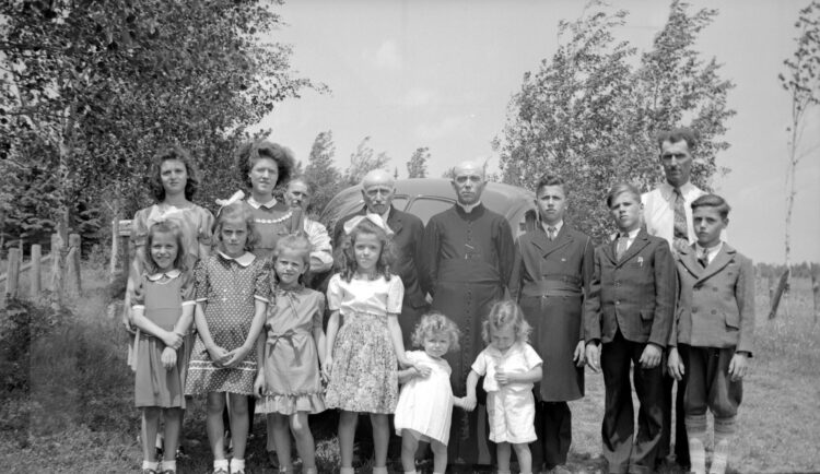 A family group of about fifteen people of all ages posing outdoors.